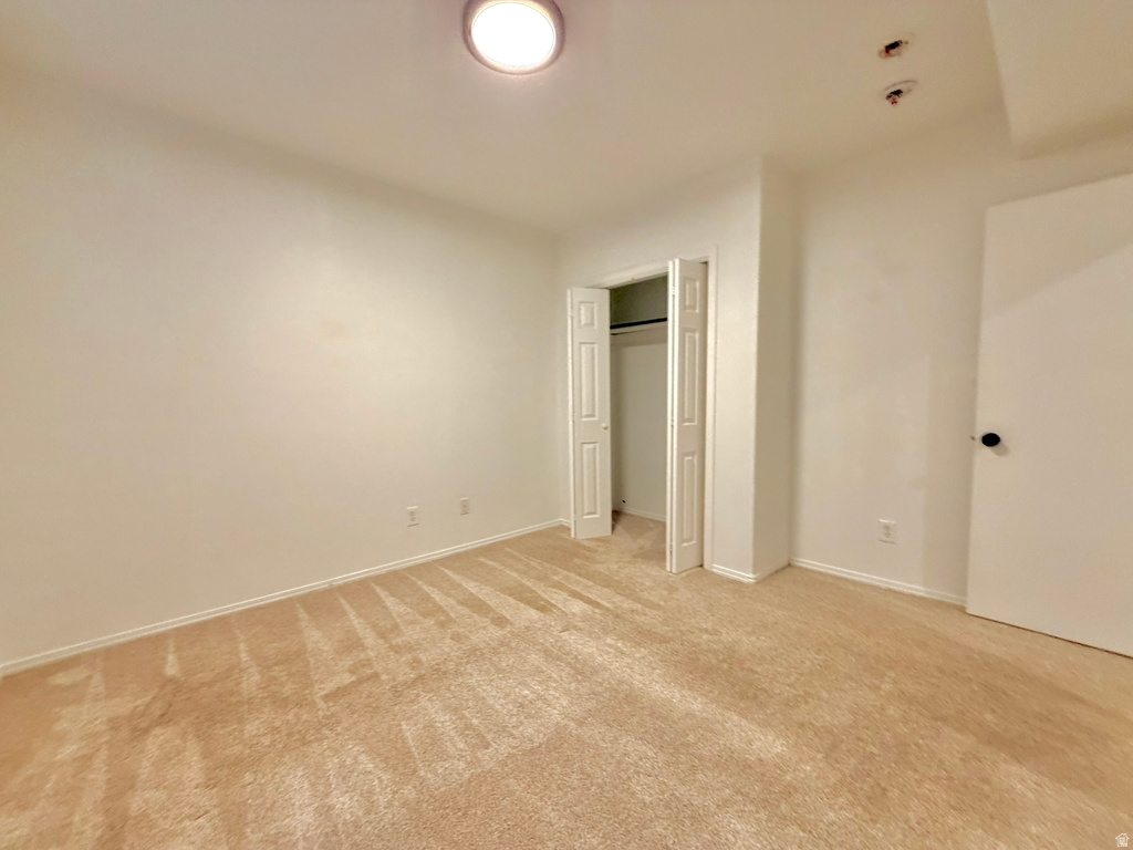 Room featuring textured beige carpeting, white walls, and a ceiling-mounted light fixture