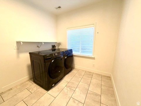 Laundry area featuring tile flooring, a window with blinds, and a wall-mounted shelf