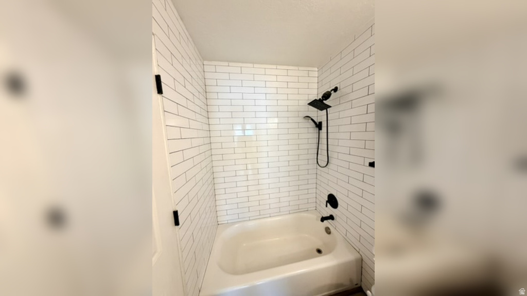 Bathtub/shower combination featuring white subway tile surround, matte black shower fixtures, and a coordinating matte black faucet