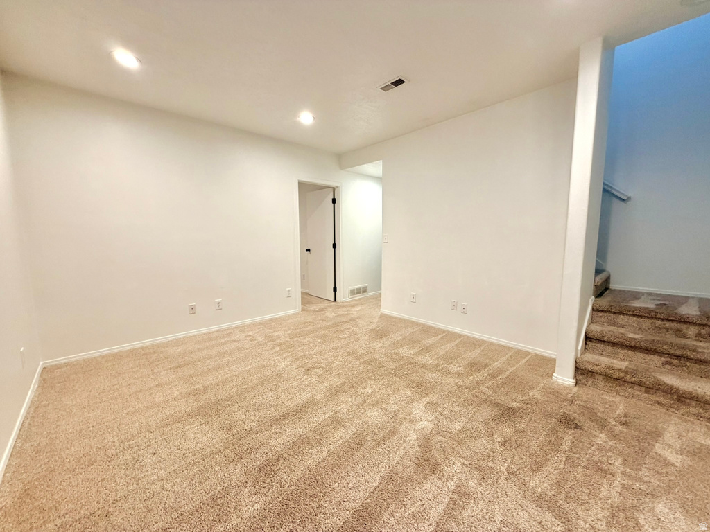 Carpeted room with recessed lighting, white baseboards, and a doorway opening into a separate area