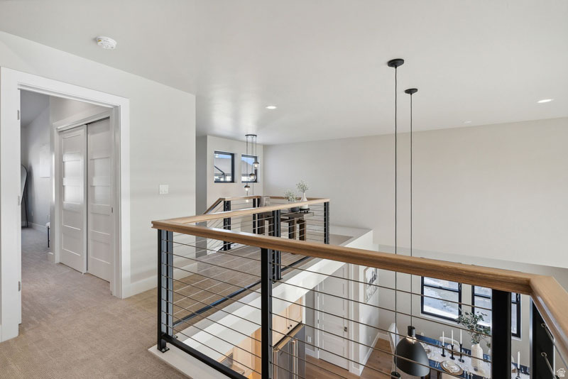 Open upper-level landing with contemporary cable railings featuring a wood-finish top rail and black metal posts