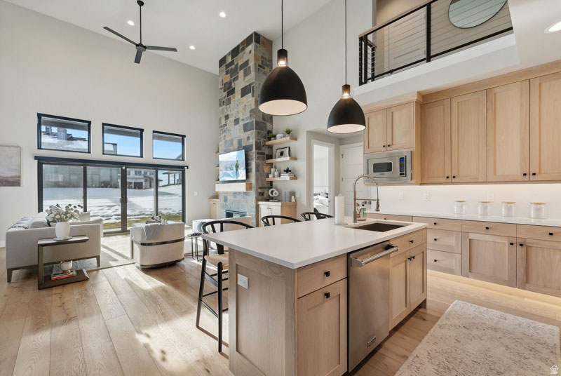 Open-concept living space featuring high ceilings, wood-finish flooring, and a stone-clad fireplace
