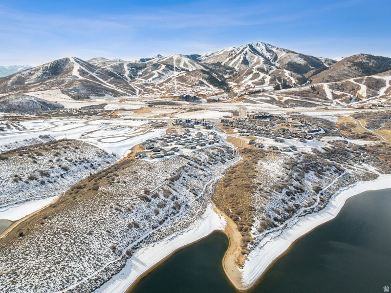 Snow-dusted mountain landscape featuring a body of water, residential development, and expansive terrain