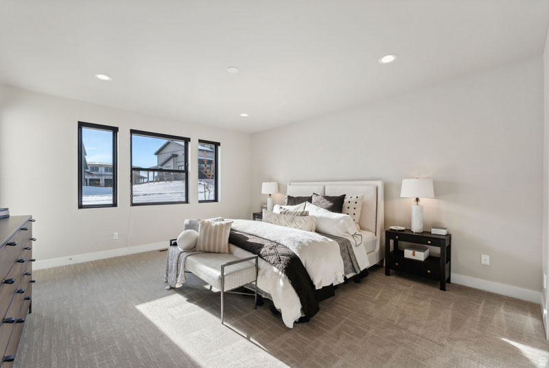 Spacious room featuring light-colored walls, recessed ceiling lighting, and three large windows with black frames