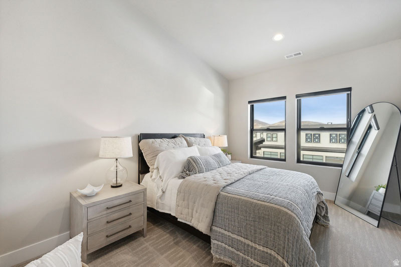 Bedroom featuring two windows with black frames, recessed lighting, and light-colored walls