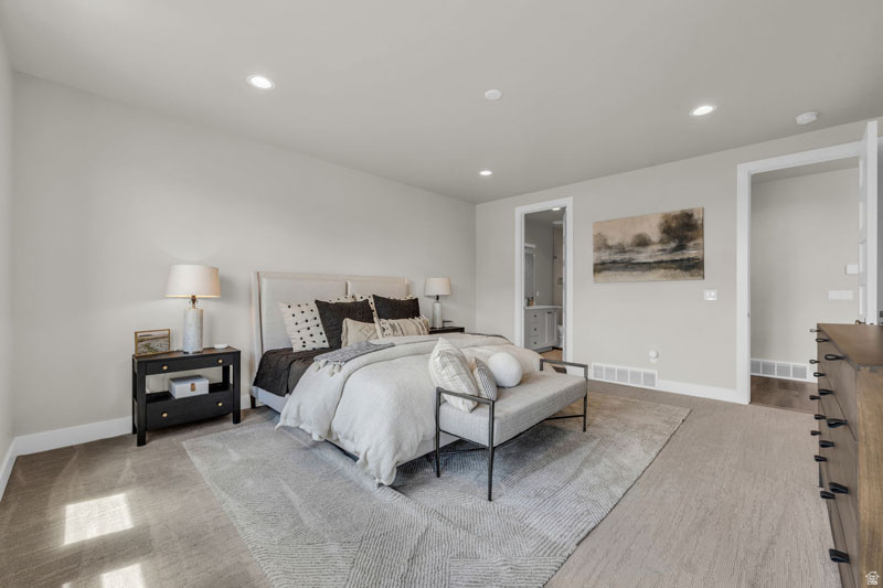 Spacious sleeping area featuring light-toned walls, recessed lighting, carpet flooring, and a large area rug