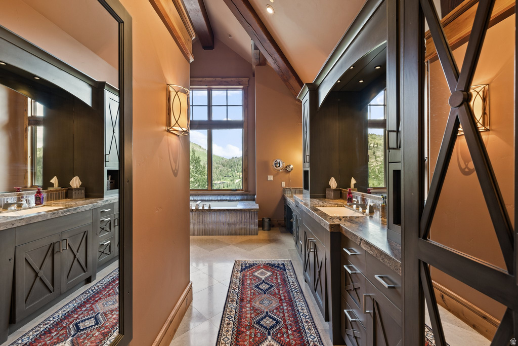 Spacious bathroom featuring twin vanities with stone countertops, integrated sinks, and dark cabinetry