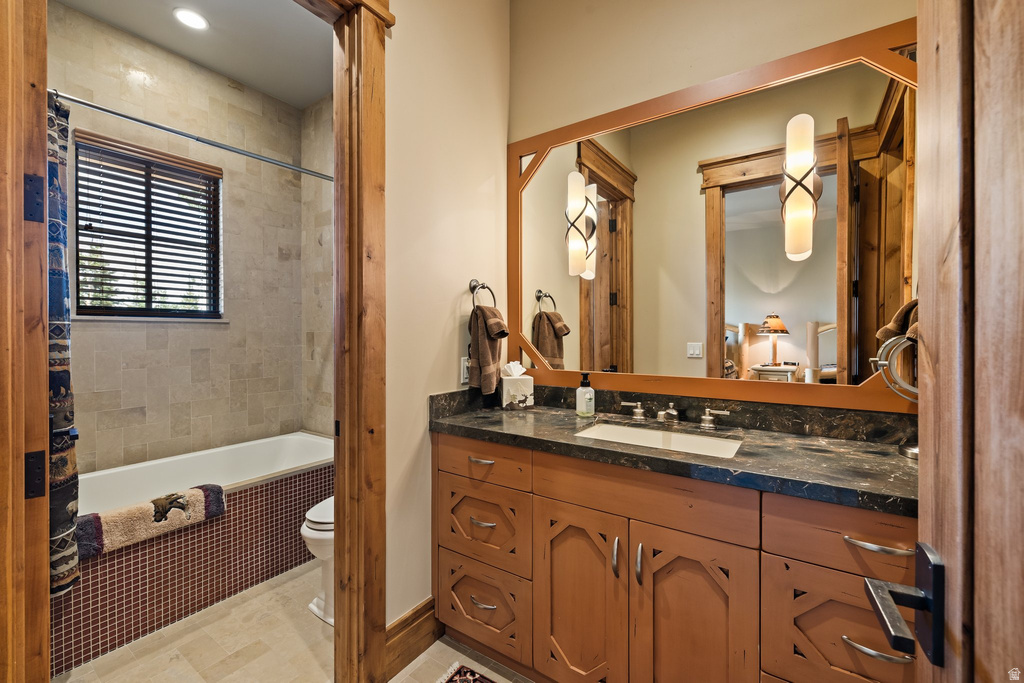 Bathroom vanity featuring a dark stone countertop, undermount sink, and custom wood cabinetry