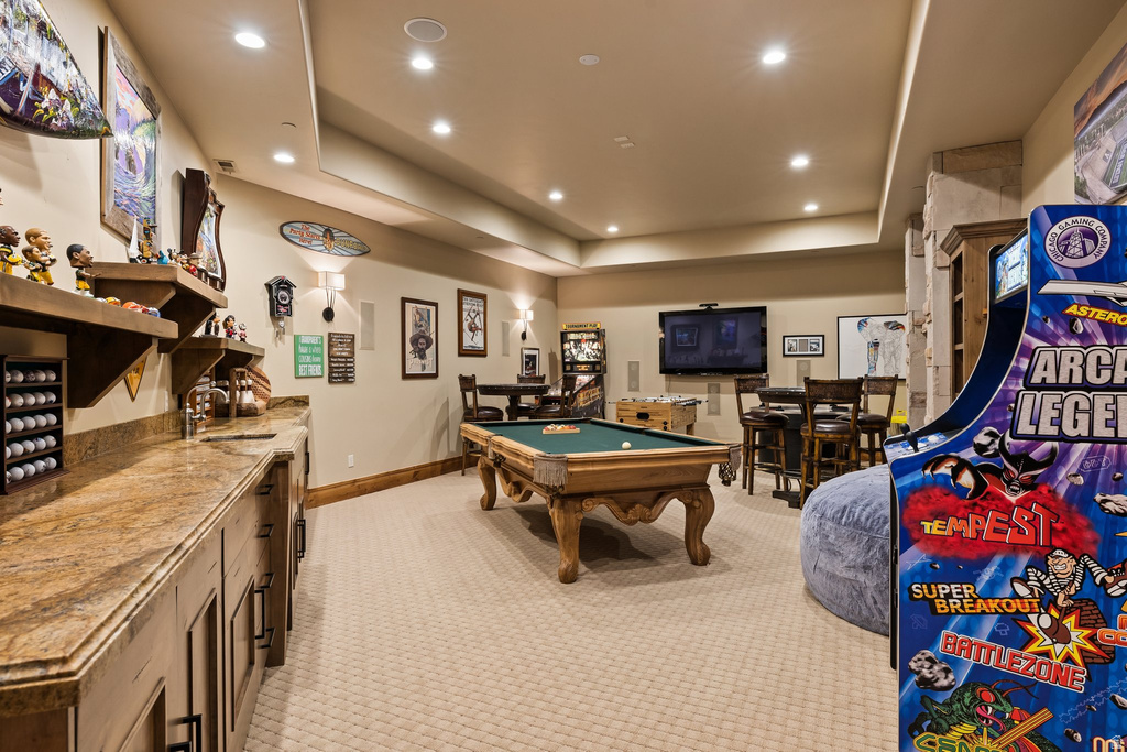Entertainment space featuring a billiards table, wall-mounted television, recessed lighting, and a built-in wet bar with a stone countertop