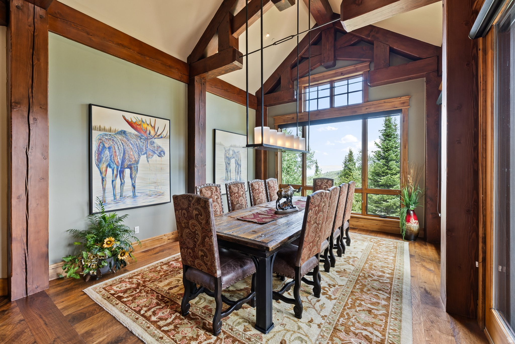 Spacious room featuring exposed wood beams, vaulted ceilings, and large picture windows