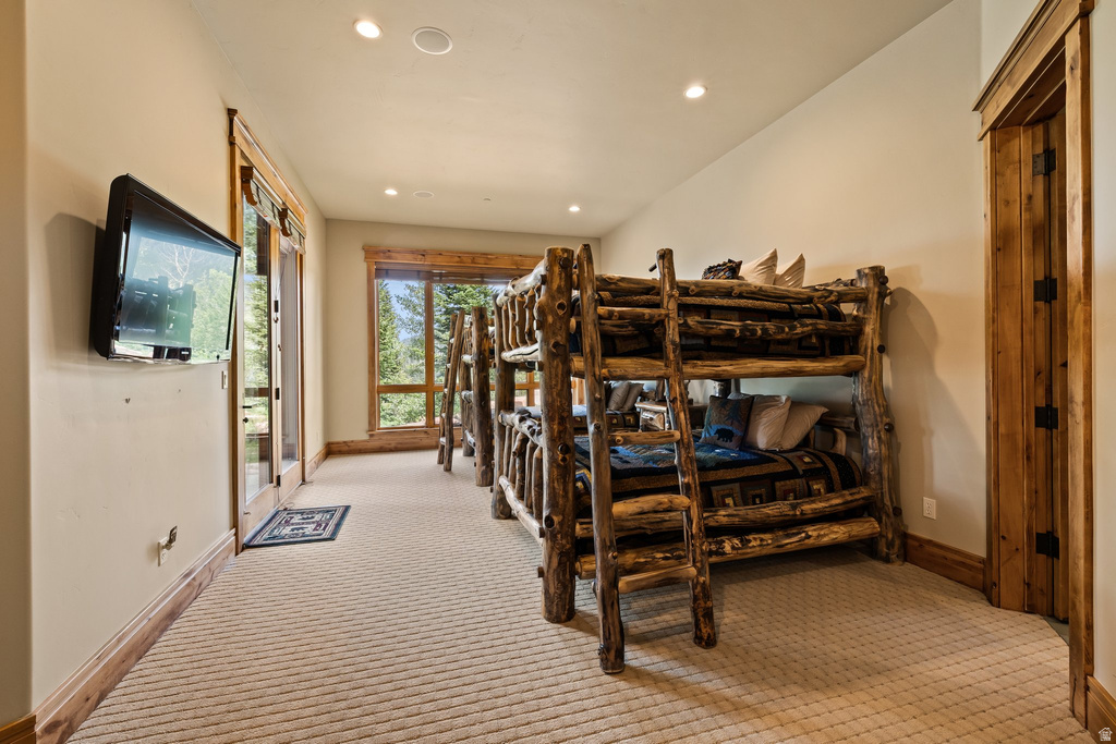 Spacious room featuring multiple rustic log bunk beds, plush patterned carpeting, and recessed lighting