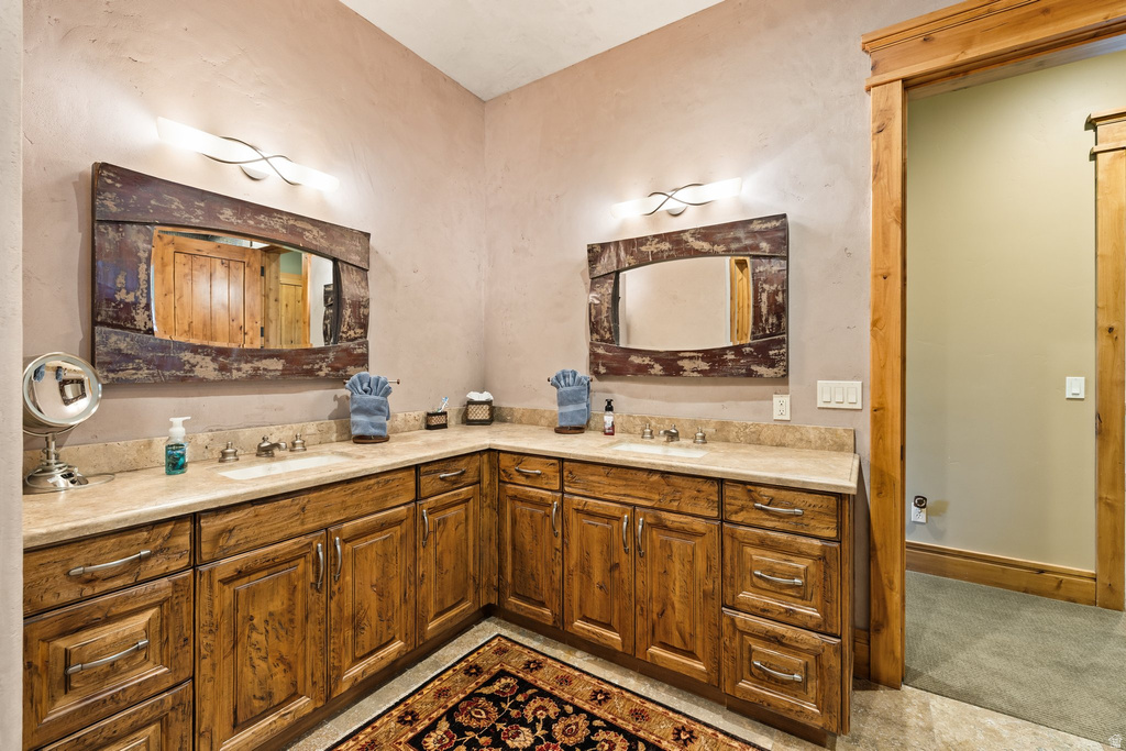 Dual vanity with wood-finish cabinetry, light-toned countertops, and integrated sinks