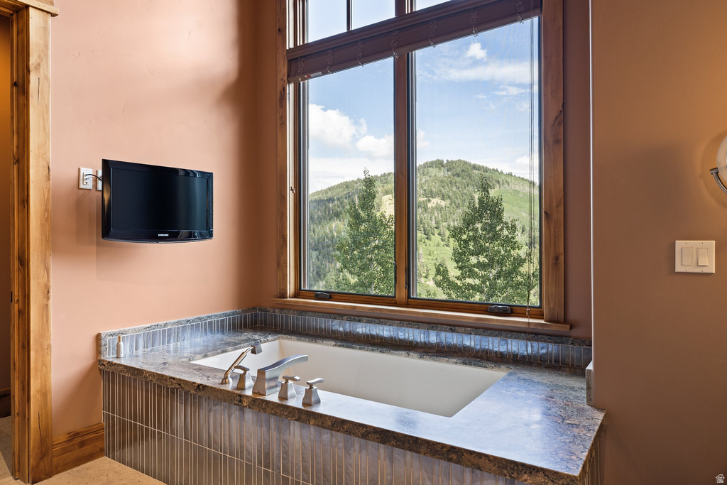 Built-in soaking tub with a stone countertop and tile surround
