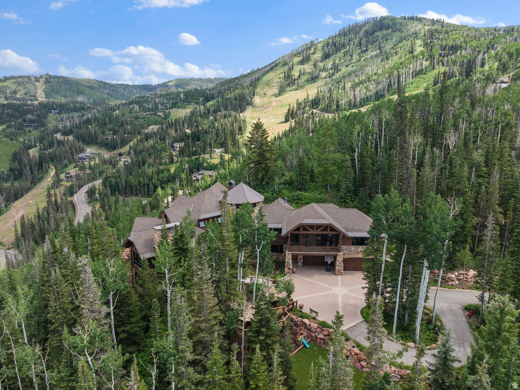 Expansive mountain-style residence featuring multiple gabled roofs, stone and wood siding, and an attached garage with a paved driveway
