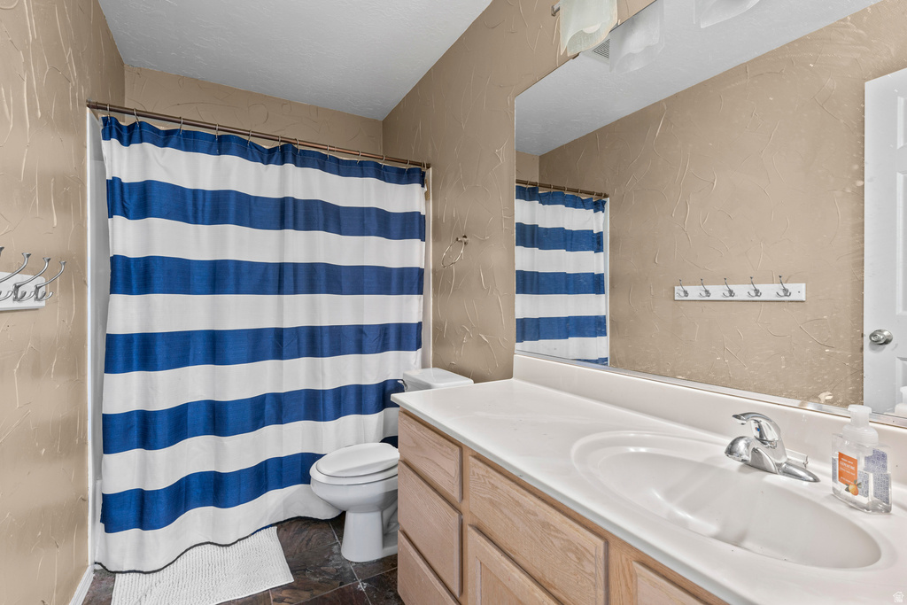 Bathroom featuring a single vanity with wood-finish cabinetry, a white countertop with an integrated sink, and a chrome faucet
