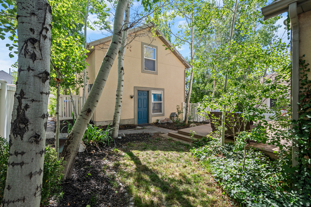 Exterior stucco home with a blue paneled door, complemented by a white privacy fence and a wood deck with steps