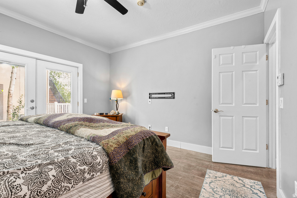 Bedroom featuring wood-finish flooring, a ceiling fan, crown molding, and double glass-paneled patio doors