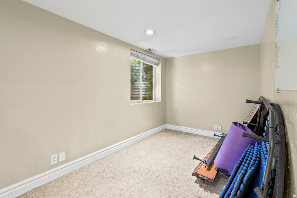 Carpeted room featuring a window with a roller blind, recessed lighting, and neutral-toned walls