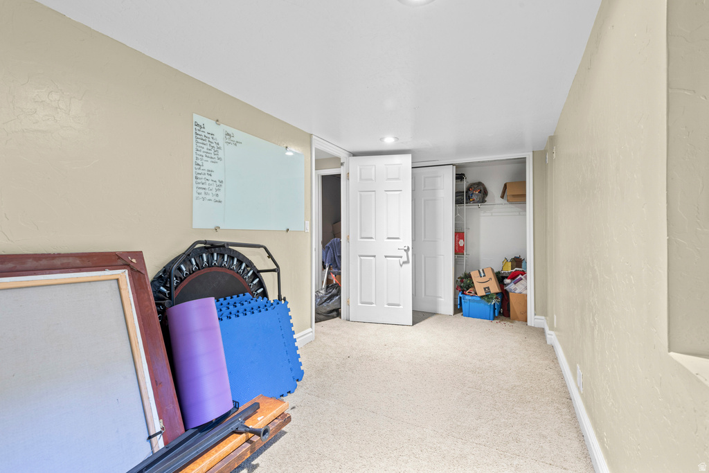 Spacious carpeted room featuring a white paneled door, built-in closet shelving, and light-toned walls