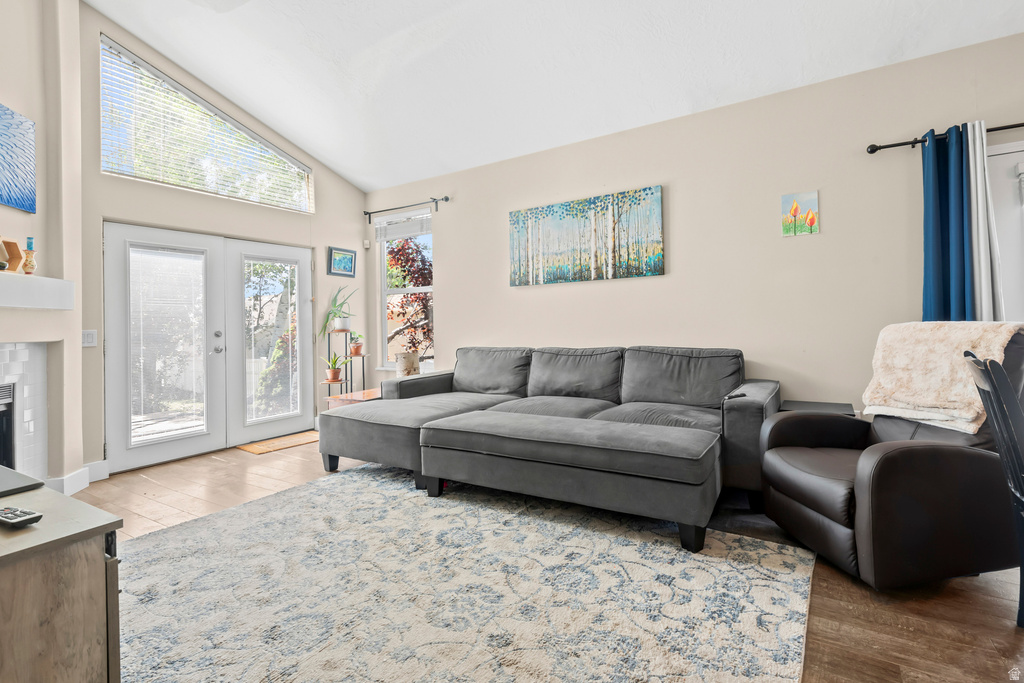 Vaulted ceiling living area featuring wood-finish flooring, a white mantel, and French doors with an overhead transom window