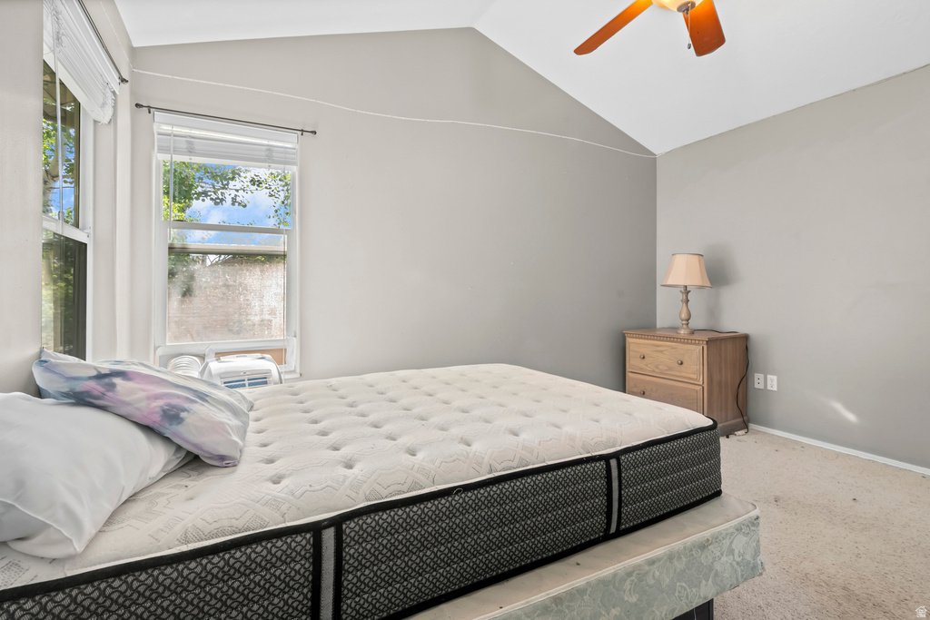 Vaulted ceiling bedroom featuring two windows with blinds, a ceiling fan, and carpeted flooring