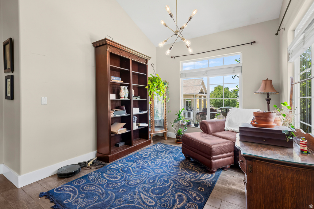 Vaulted ceiling featuring a modern chandelier, large picture windows, wood-finish flooring, and a built-in dark wood bookcase