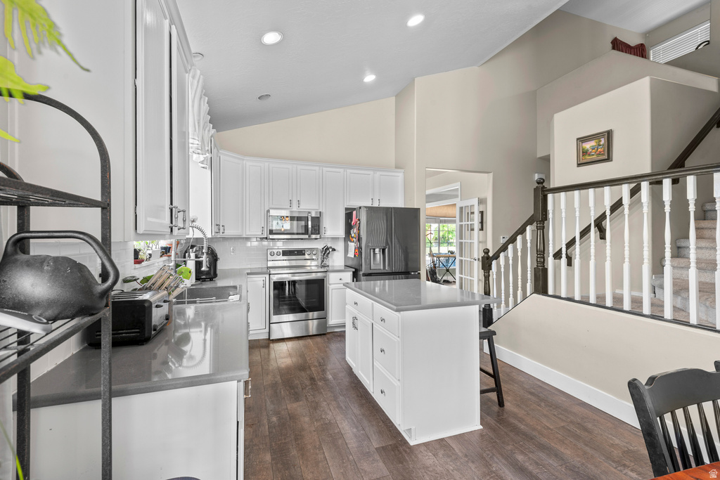 Bright kitchen featuring white cabinetry, stainless steel appliances, a center island with countertop seating, and wood-finish flooring