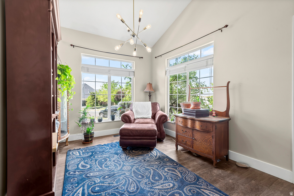 Vaulted ceilings with a contemporary chandelier, dual large windows, wood-finish flooring, and light-toned walls