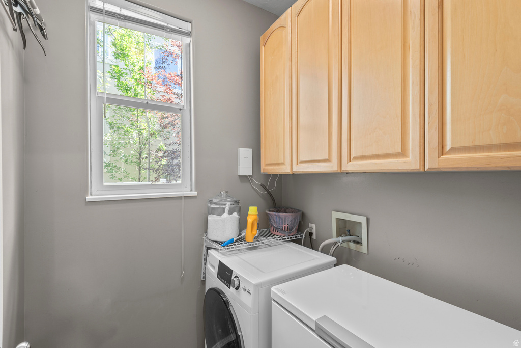 Light-filled utility space featuring a single-pane window, overhead cabinetry with light wood-finish doors, and a built-in wire shelving unit