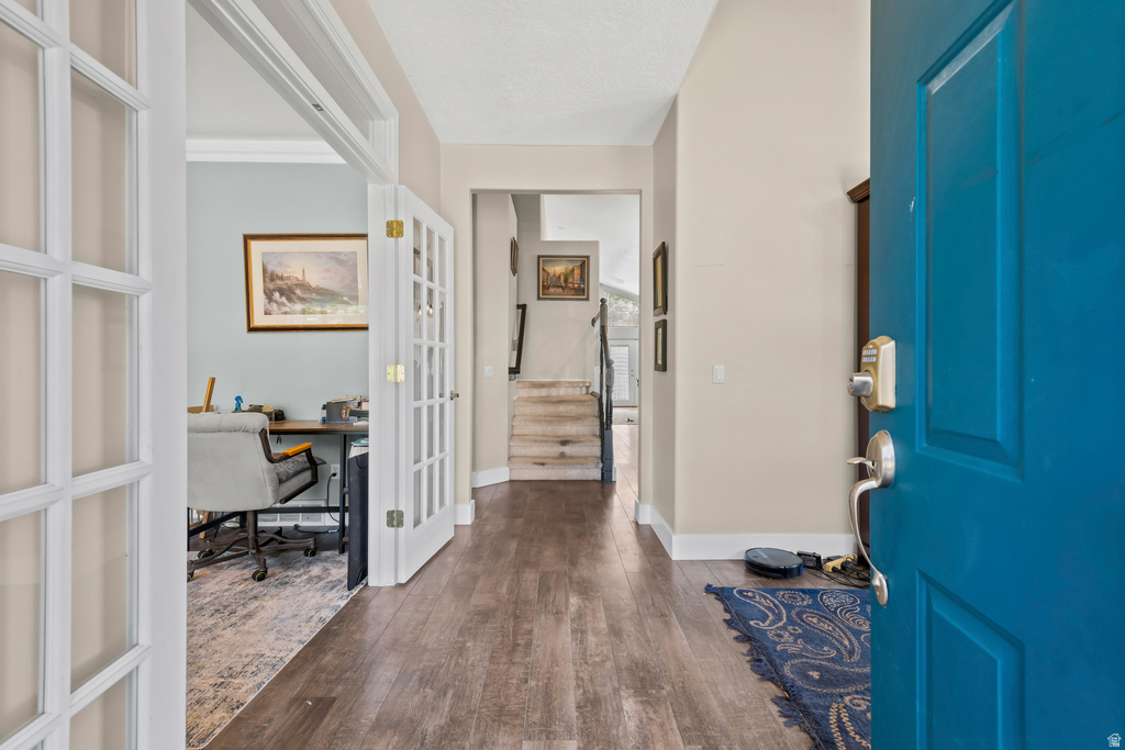 Entryway featuring wood-finish flooring, a vibrant blue front door with brushed nickel hardware, and French doors opening to an interior room