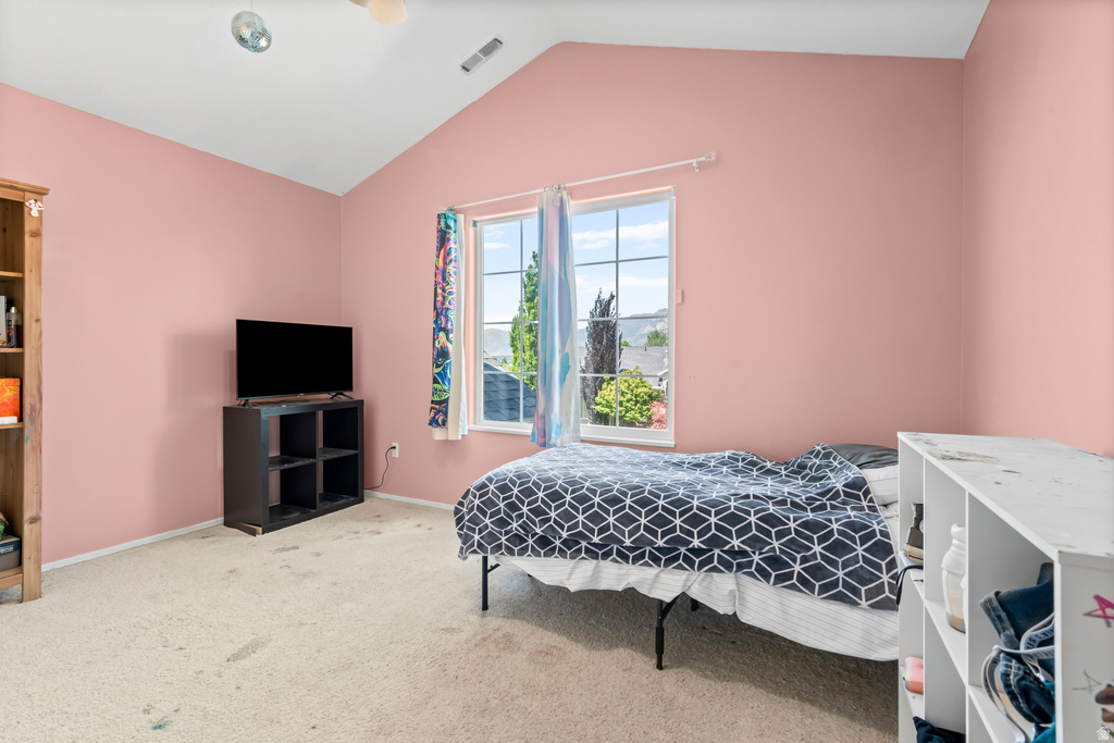 Vaulted ceiling room with an exterior window, carpeted flooring, and a ceiling fan