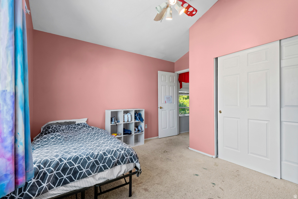 Room featuring sloped ceilings, a ceiling fan with light fixture, and light-colored carpeting