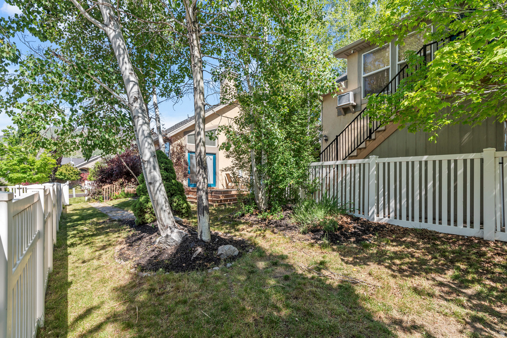 Expansive outdoor space featuring a white privacy fence, mature trees, and landscaping