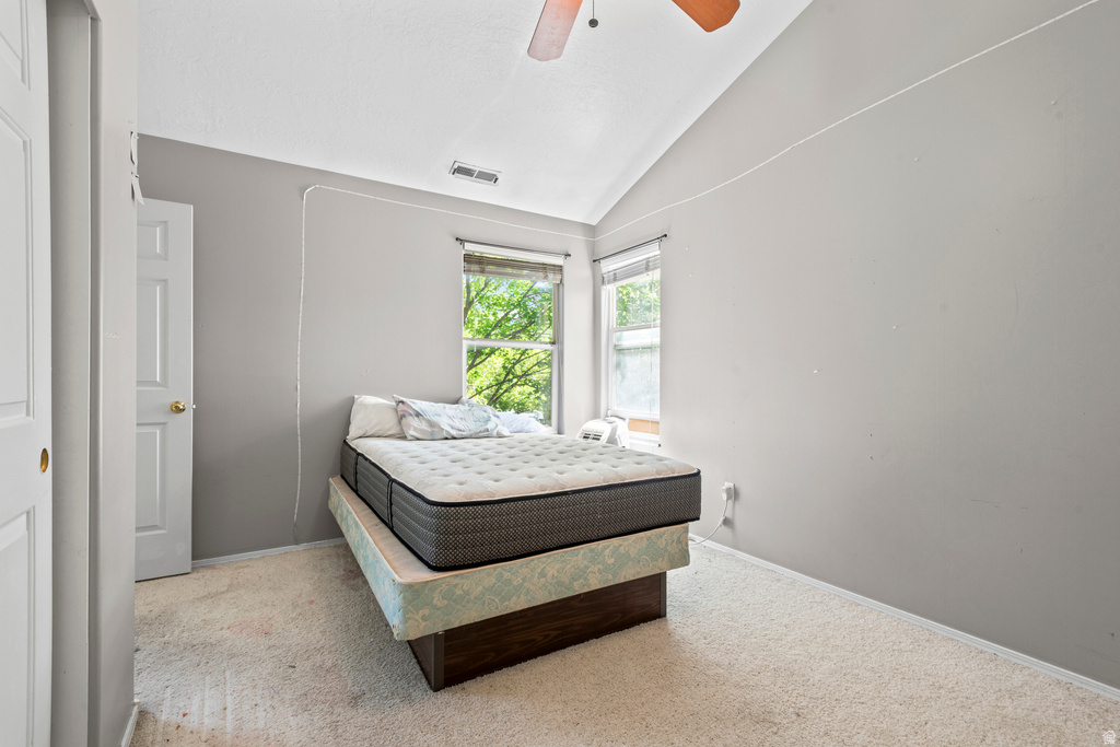Room with vaulted ceiling, two windows, and light neutral carpet