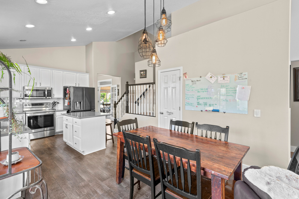 Kitchen and dining area featuring wood-finish flooring, white cabinetry, stainless steel appliances, and a kitchen island with storage