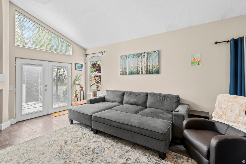 Living area featuring wood-finish flooring, vaulted ceiling, and ample natural light from multiple windows