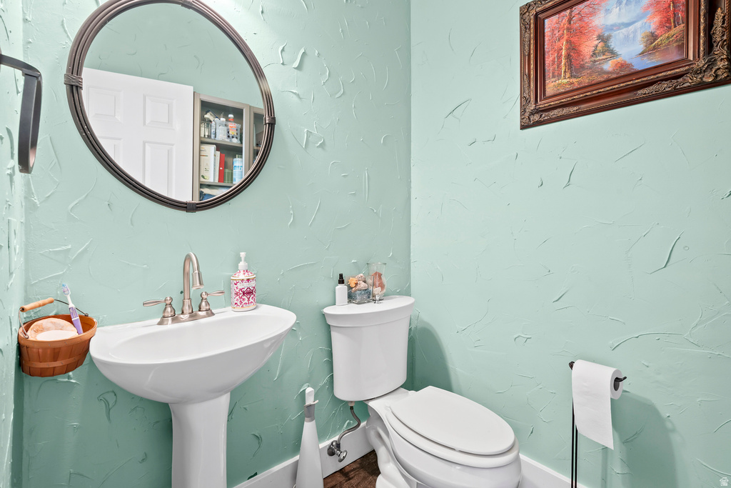 Pedestal sink with brushed nickel faucet, wall-mounted oval mirror, and textured wall finish