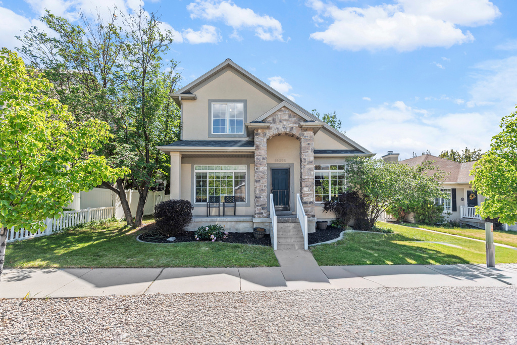 Stucco and stone facade home featuring a prominent arched entryway