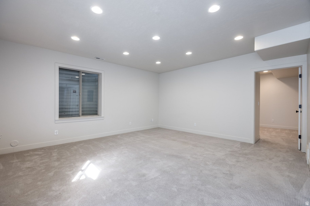 Spacious room with light gray carpeting, recessed ceiling lighting, a single window, white walls, and white baseboards