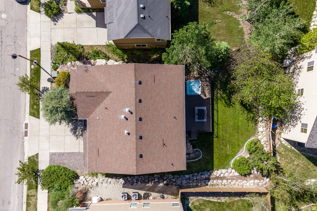 Aerial perspective showcasing a brown shingle roof, a rear wood deck, a built-in hot tub, and a spacious green lawn