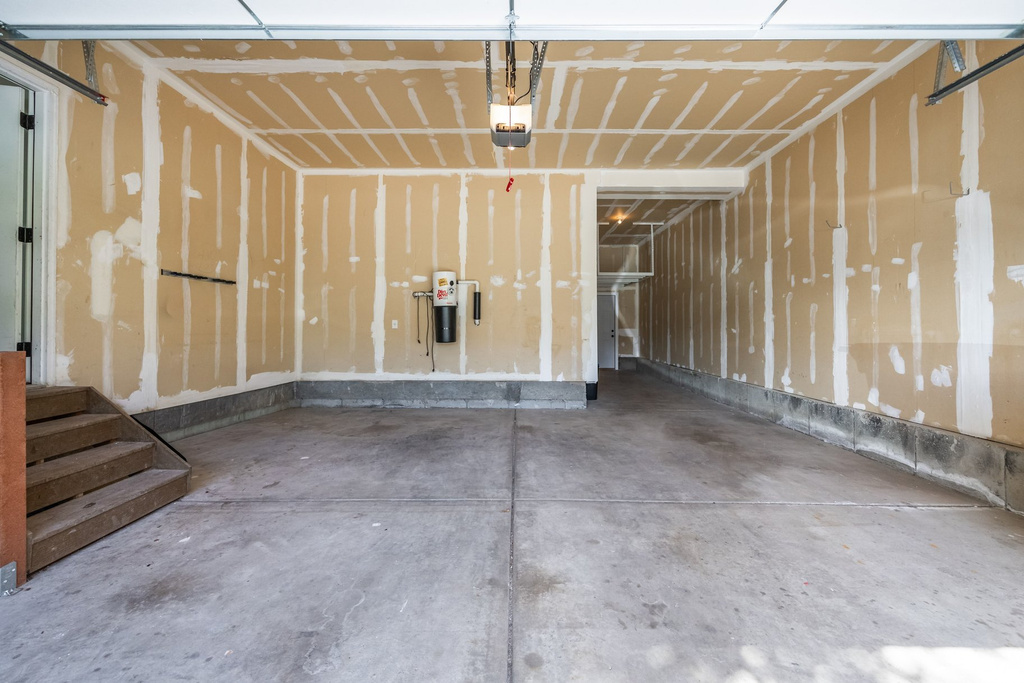 Spacious garage with concrete flooring, automatic garage door opener, and unfinished walls ready for customization