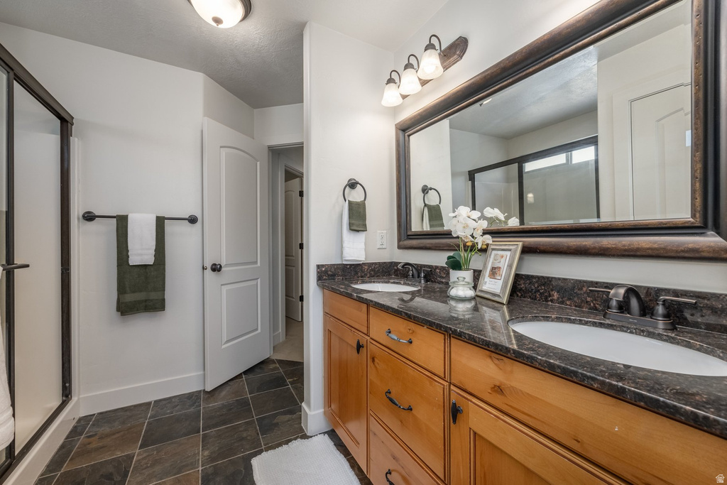 Dual vanity with dark countertops, integrated sinks, and wood-finish cabinetry