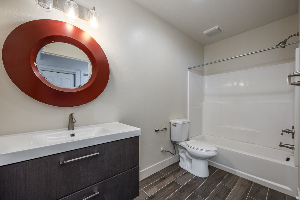 Bathroom featuring a floating wood-finish vanity with an integrated sink, a circular red-framed mirror, and a three-light vanity fixture