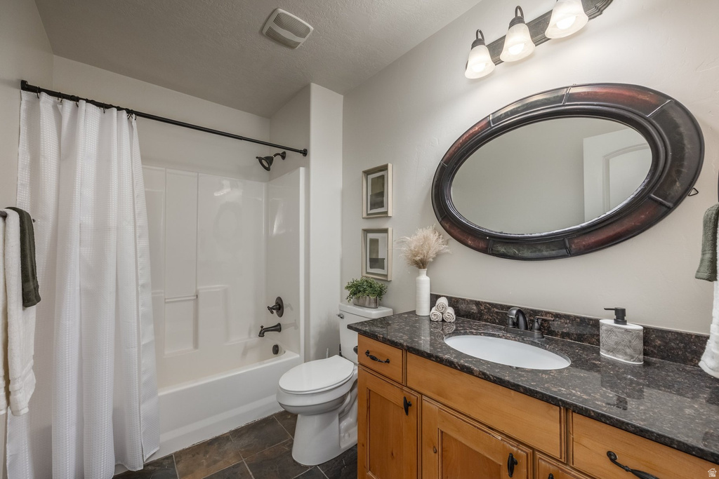 Bathroom featuring a wood-finish vanity with an integrated sink and dark stone countertop