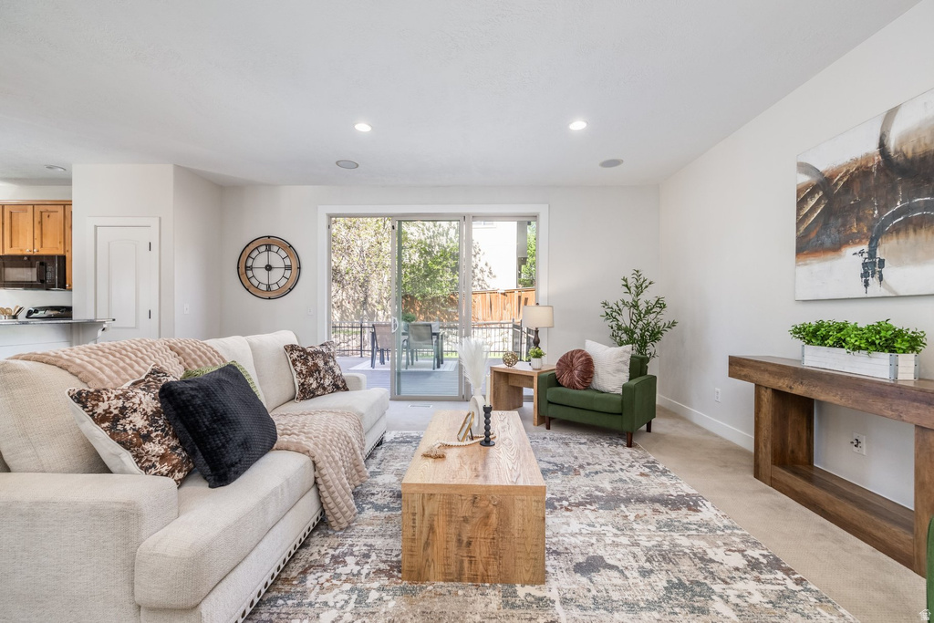 Spacious living area featuring light-toned walls, recessed lighting, and direct access to an outdoor patio through sliding glass doors