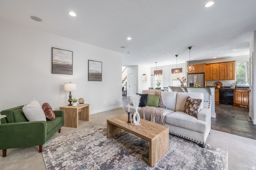 Open-concept living area featuring recessed ceiling lights, light-toned wall finishes, and carpeted flooring