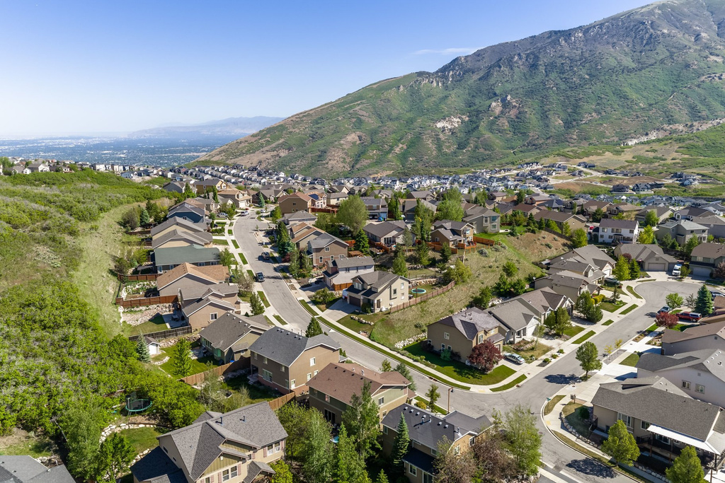 Residential neighborhood with paved streets and mature landscaping, bordered by a large natural hillside