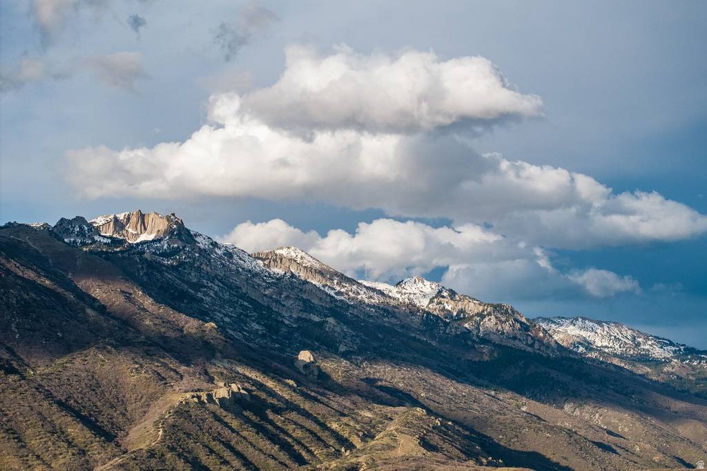 Expansive mountain landscape featuring rugged peaks and scattered snowcaps