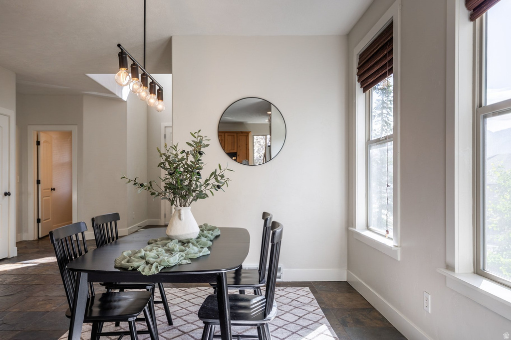 Dining area featuring dark slate flooring and a rectangular dining table with four chairs