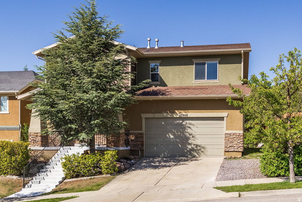 Two-story residence featuring a stucco exterior with stone accents and an attached garage